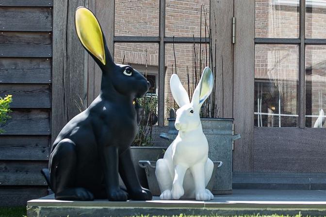 Statues of two modern hares in black and gold and white and silver on a patio Garden ID