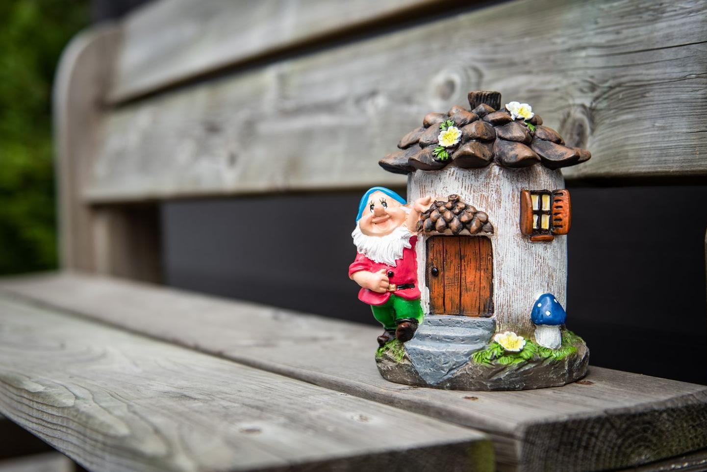 A garden gnome with his little house on a wooden bench Garden ID