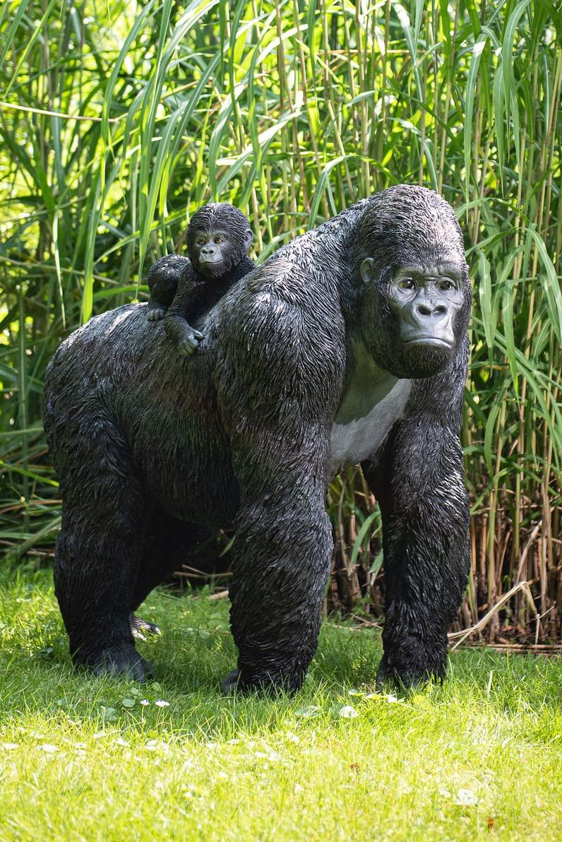 Gorillabeeld staand met zijn baby op zijn rug voor bamboebomen in een tuin Garden ID